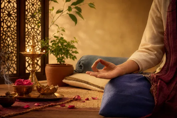 A quiet evening meditation setting with relaxed hands in a mudra, soft lamp light, and calm bedroom atmosphere.